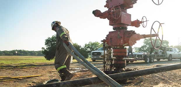 man with hose at wellhead